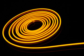 Flexible yellow led tape neon flex in roll on black background.