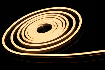 Flexible warm white led tape neon flex in roll on black background.