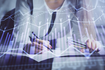 Double exposure of hands making notes with forex chart huds. Stock market concept.