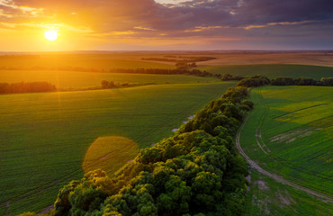 Fototapeta na wymiar Aerial top view of green rural area under colorful sky at sundown.