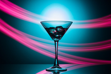 Martini glass with drink and ice, with a spectacular illumination of the background.