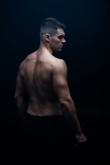 Obraz na płótnie Canvas back view of sexy muscular bodybuilder with bare torso posing isolated on black