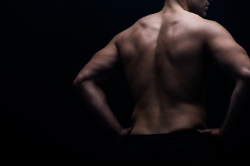 partial view of sexy bodybuilder with muscular back posing isolated on black