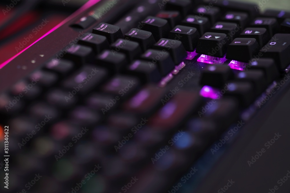 Poster close up of computer rgb gaming keyboard, illuminated by colored led