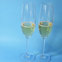 Glasses with champagne stand on a blue background, a yellow lemon lies.