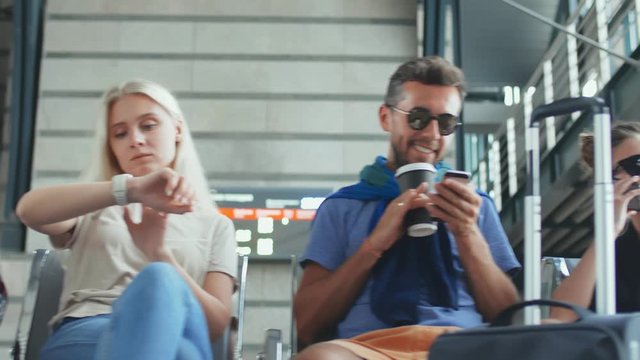 Tourists sitting in airport waiting for hall and using gadgets or drinking coffee waiting for flight.