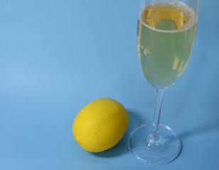 Glasses with champagne stand on a blue background, a yellow lemon lies.