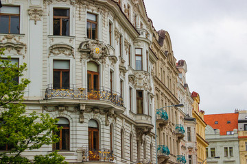 Facade of typical colorful czech houses with trees at the foreground in Prague, Czech Republic