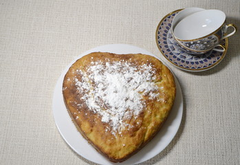 Homemade baking. On the table there is a form with a freshly baked tasty pie made from yeast dough, sprinkled with powdered sugar.