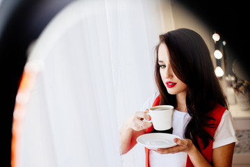 Beautiful woman with red lips holds a cup of coffee.