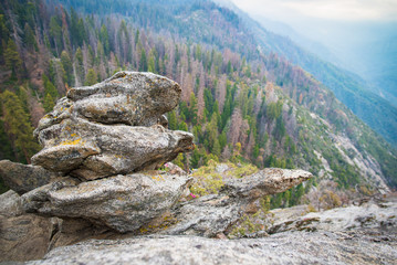 Scenic view to Sequoia and Kings Canyon NP giant forests and foggy valleys landscape of Sierra Nevada mountain range. Granit boulder on Moro Rock hiking track in Sequoia National Park, California