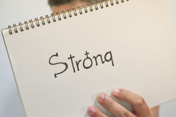 Closeup of a people showing book with the text strong and gender symbol of female.
