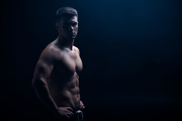 sexy muscular bodybuilder with bare torso posing with hands on hips isolated on black