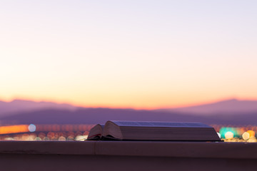 a book at sunset with the mountains in the background; amazing landscape view during blue hour.