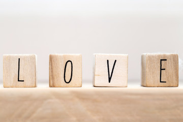 Word Love on wooden cubes with red heart, close-up near white background