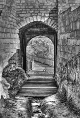 A look thru an opened stone gate of an ancient fortress in black and white