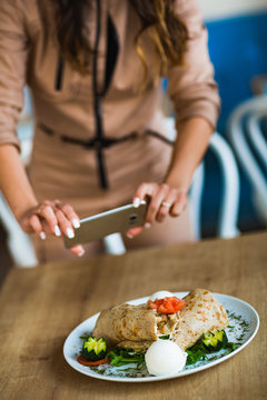 Female food blogger taking photos for their food blog using mobile phones