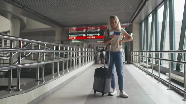 Young woman in airport waiting for air travel looking at ticket and passport