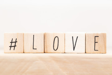 Word Love on wooden cubes with Hashtag, close-up near white background