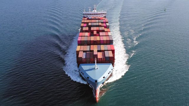 Large loaded Container Ship roaring across the open sea, Aerial view.
