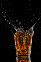 Glasses of whiskey with splash, isolated on black background