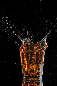 Glasses of whiskey with splash, isolated on black background