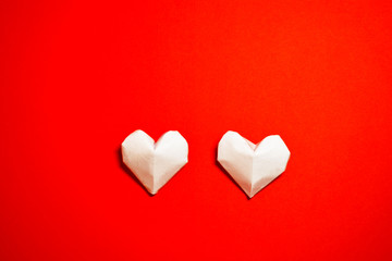 The Background Of Valentine's Day. Two white origami paper hearts, on a red background. The Concept Of Valentine's Day. Flat lay. Top view, copy space.