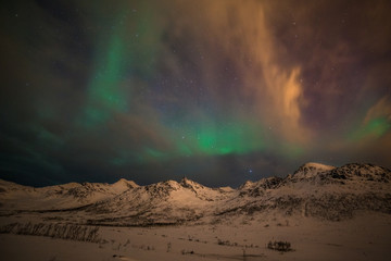Obraz na płótnie Canvas Dramatic polar lights, Aurora borealis with many clouds and stars on the sky over the mountains in the North of Europe - Tromso, Norway.long shutter speed.