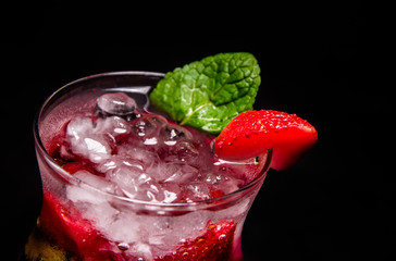 Berry Mojito with lime. Close-up of strawberries, mint and ice. Beautiful cocktail on an isolated black background.