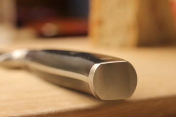 Macro of a steel knife on a wooden desk.