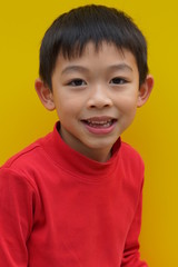 The lovely and smiley Asian boy with the plain yellow background.