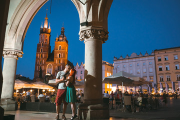 Fototapeta na wymiar Happy couple in love on the street near the Wavel castle in Krakow, have a rest and enjoy the evening view of the city. Poland. Tourism travel concept, copy space. Man and woman, romantic