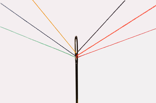 multiple colorful threads passing through the eye of a needle
