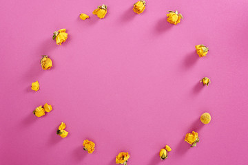 Flowers composition. Frame made of yellow rose flowers on pink background. Flat lay, top view, copy space