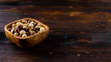 hazelnuts in a wooden bowl on a wooden background