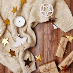 Cozy Winter Composition. Christmas Gifts, Gold Stars, Warm Knitted Sweater on Wood Background....
