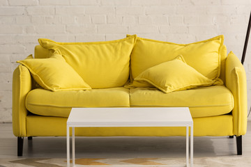 Yellow couch with cushions and white coffee table in living room