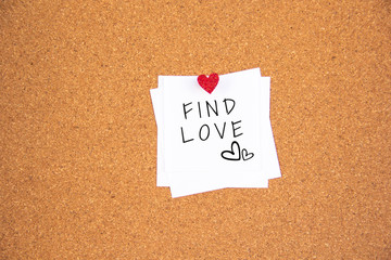 Find love lettering on white paper pinned with small glowing heart pushpin on cork board