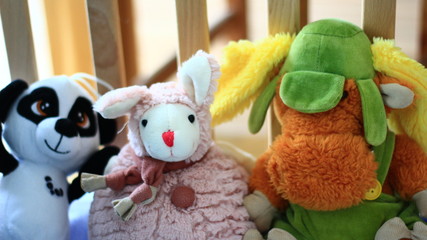 Vivid plush toys for baby in a wooden baby cot.