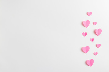 Composition for Valentine's Day February 14th. Delicate composition of pink hearts made of paper on a white background. Heart cut out of paper. Greeting card. Flat lay, top view, copy space.