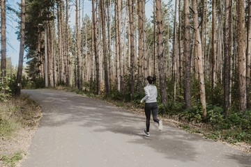 Runner athlete running on a forest trail. woman fitness running workout Wellness concept. girl on a run in the woods. A young fitness athlete runs along the Park trail