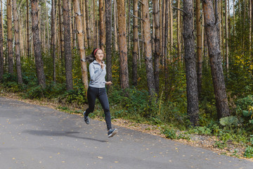 Runner athlete running on a forest trail. woman fitness running workout Wellness concept. girl on a run in the woods. A young fitness athlete runs along the Park trail