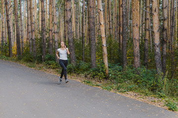 Runner athlete running on a forest trail. woman fitness running workout Wellness concept. girl on a run in the woods. A young fitness athlete runs along the Park trail