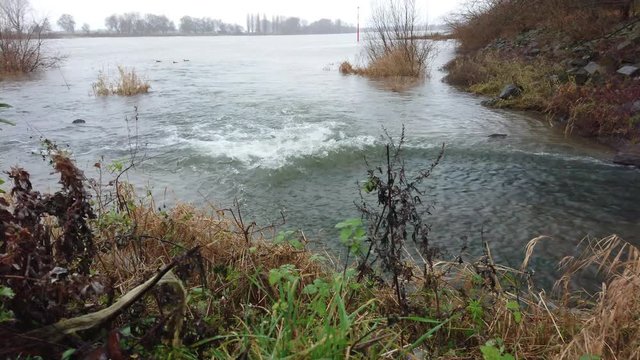 Flowing water at creek mouth to the river on a cloudy day