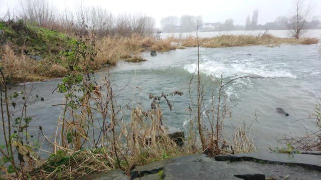 Flowing water at creek mouth to the river on a cloudy day