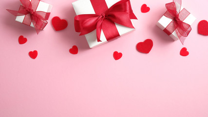 Valentines day concept. Pink background with white gift boxes and red hearts. Flat lay, top view.