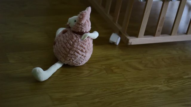 Small plush toy in the front of wooden baby cot.