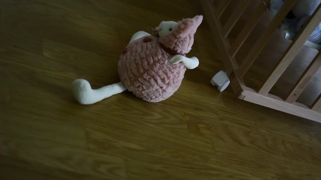 Small plush toy in the front of wooden baby cot.