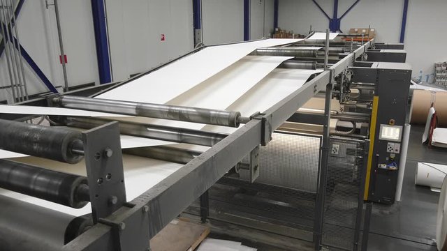 White paper moving fast at conveyor of printing factory