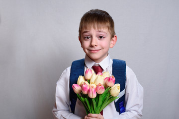 Schoolboy with a school bag holding a bouquet of tulips. White background